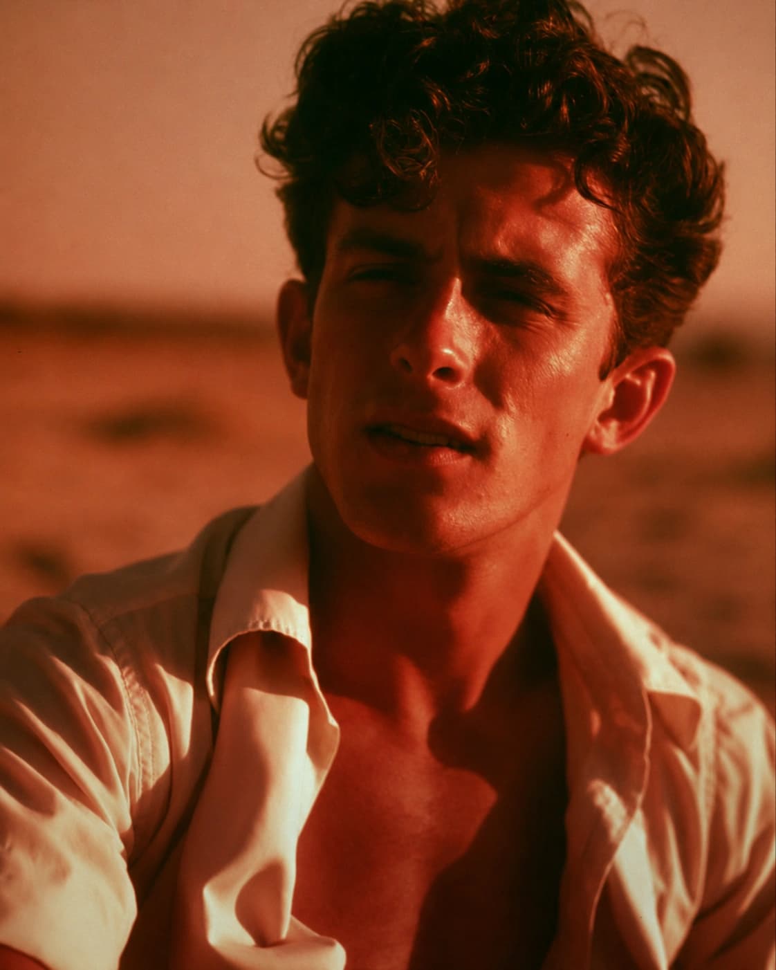 Portrait in warm desert light, white shirt open at the collar.